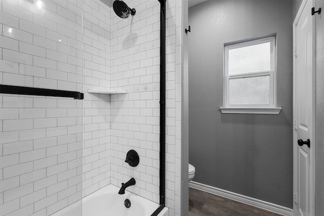 bathroom with hardwood / wood-style floors, tiled shower / bath combo, and toilet