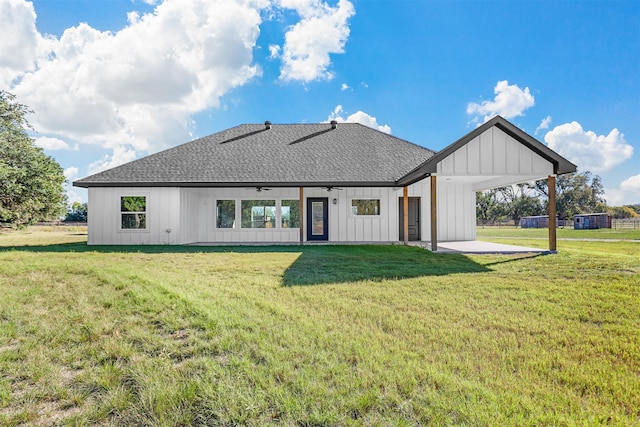 rear view of property featuring a carport, ceiling fan, and a lawn