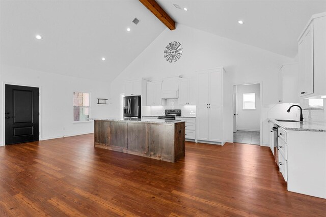 kitchen featuring beam ceiling, dark wood-type flooring, a kitchen island, and stainless steel appliances