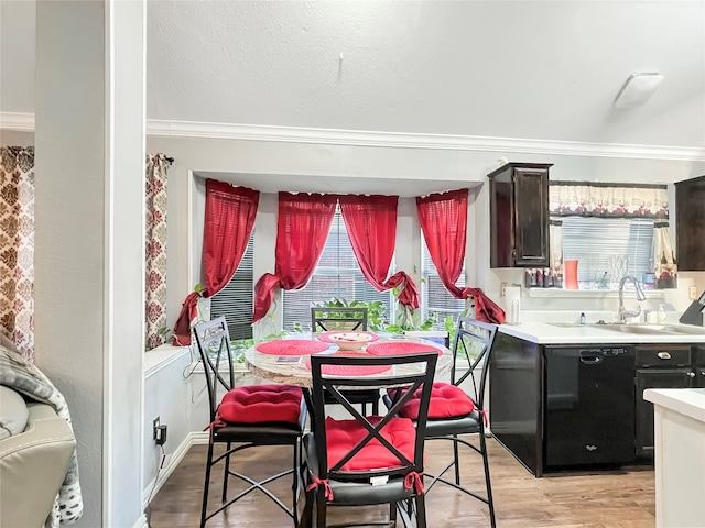 dining area featuring crown molding, sink, a textured ceiling, and light wood-type flooring