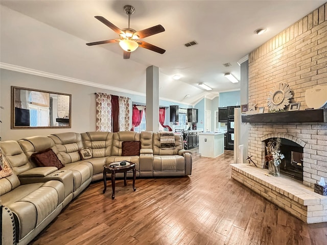 living room featuring ornamental molding, vaulted ceiling, ceiling fan, a fireplace, and light hardwood / wood-style floors