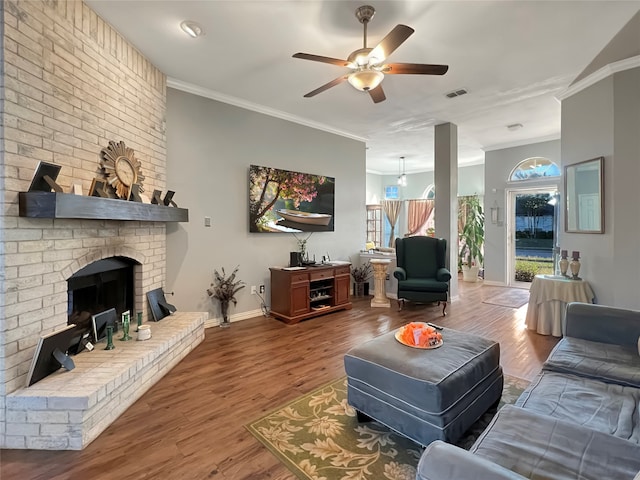 living room featuring ceiling fan, a fireplace, wood-type flooring, and ornamental molding