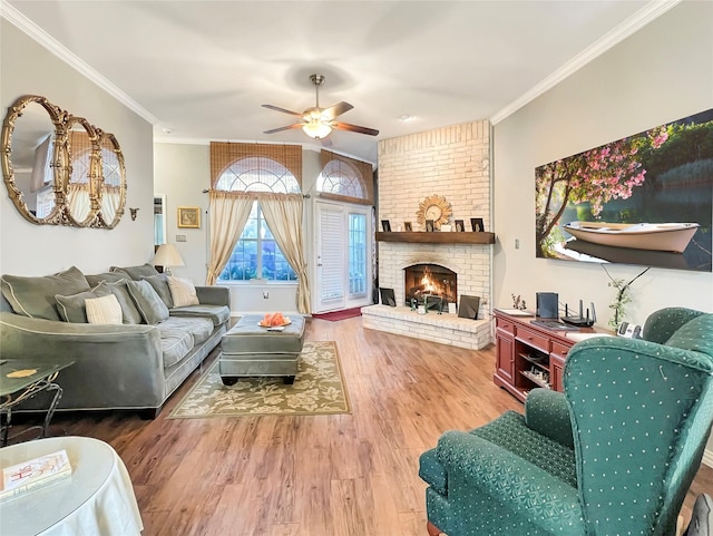 living room with a brick fireplace, wood-type flooring, ornamental molding, and ceiling fan