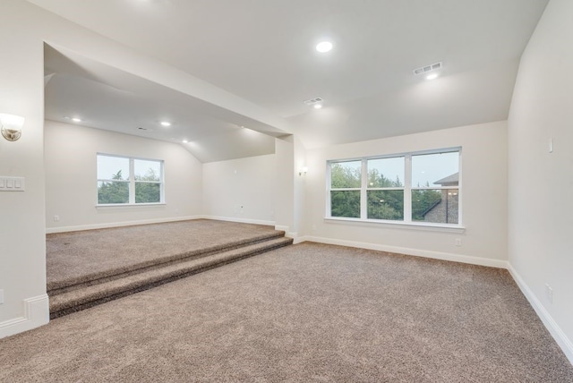 carpeted spare room featuring vaulted ceiling