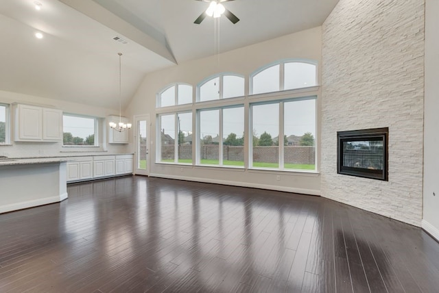 unfurnished living room with a fireplace, high vaulted ceiling, dark hardwood / wood-style flooring, and ceiling fan with notable chandelier