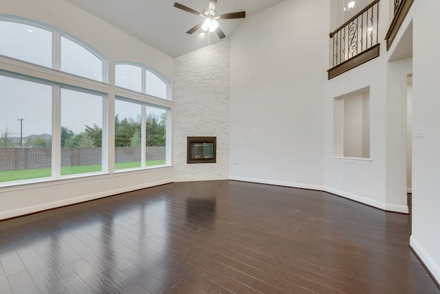 unfurnished living room with dark hardwood / wood-style flooring, a fireplace, high vaulted ceiling, and a healthy amount of sunlight