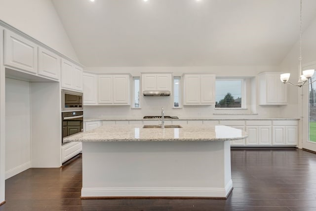 kitchen featuring built in microwave, white cabinetry, light stone countertops, and decorative light fixtures