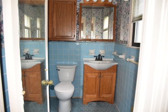 bathroom featuring toilet, vanity, tile patterned floors, and tile walls