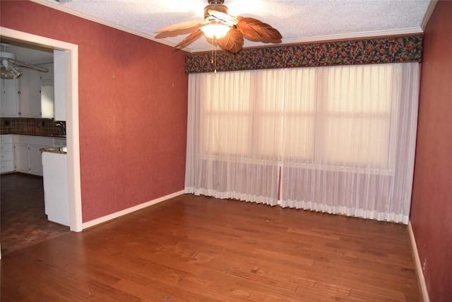 empty room with ceiling fan, crown molding, wood-type flooring, and a textured ceiling