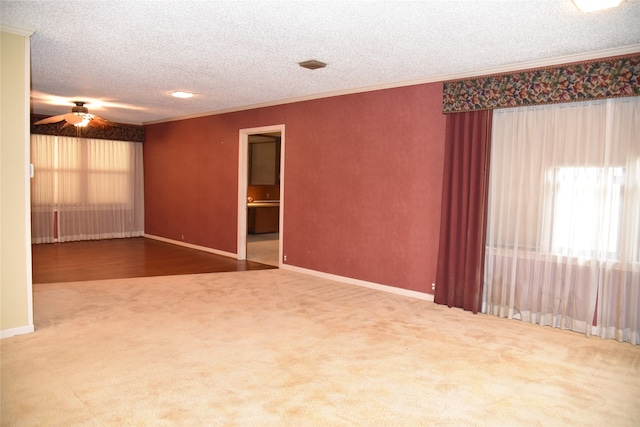 carpeted empty room with a textured ceiling, ceiling fan, and crown molding