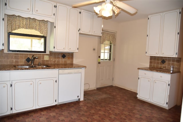 kitchen with backsplash, white dishwasher, white cabinets, sink, and dark stone countertops