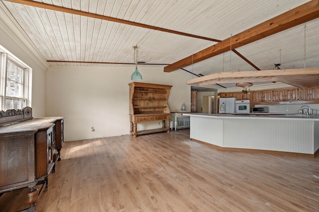 unfurnished living room with light wood-type flooring, wooden ceiling, vaulted ceiling with beams, and a sink