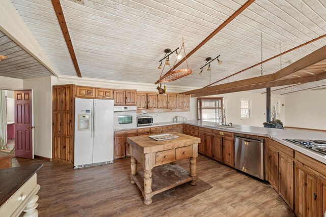 kitchen with lofted ceiling with beams, appliances with stainless steel finishes, a sink, and wood finished floors