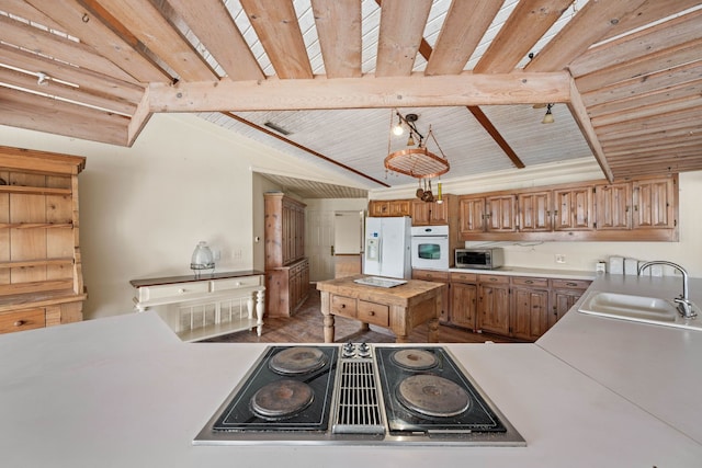 kitchen featuring white appliances, wood ceiling, vaulted ceiling with beams, light countertops, and a sink