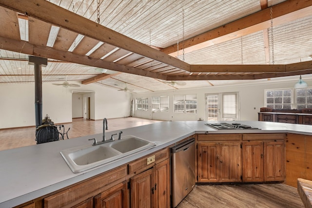 kitchen with brown cabinetry, stovetop with downdraft, vaulted ceiling with beams, stainless steel dishwasher, and a sink