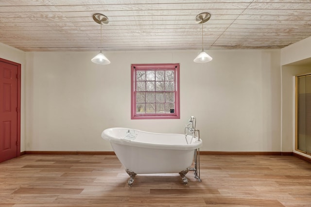 full bathroom featuring a freestanding tub, baseboards, and wood finished floors