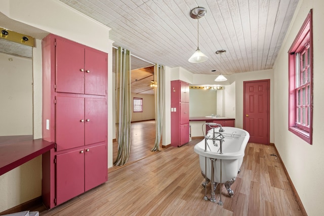 interior space featuring light wood-style floors, wooden ceiling, a sink, and baseboards