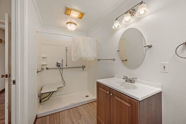 bathroom with vanity, a shower, crown molding, and wood finished floors