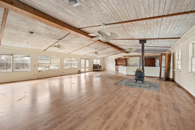 unfurnished living room featuring lofted ceiling with beams, wooden ceiling, wood finished floors, and a wood stove