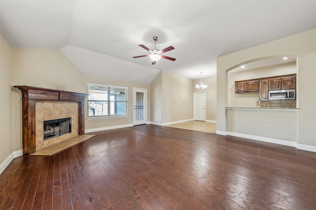 unfurnished living room featuring a tile fireplace, hardwood / wood-style floors, ceiling fan with notable chandelier, and lofted ceiling