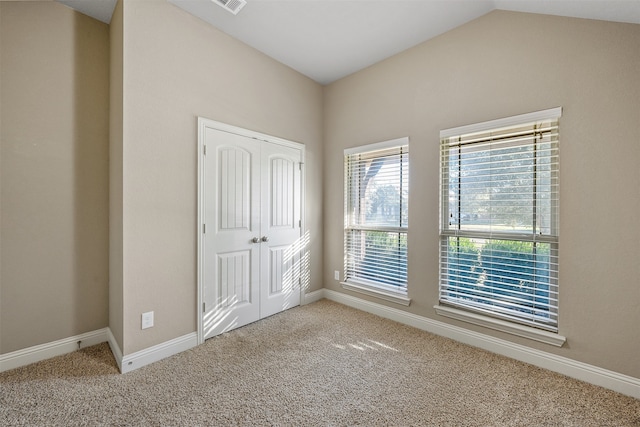 unfurnished bedroom featuring carpet floors, vaulted ceiling, and a closet