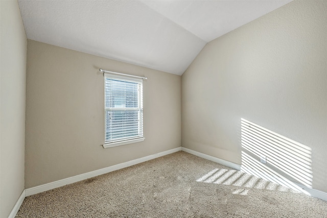 carpeted spare room featuring a textured ceiling and vaulted ceiling