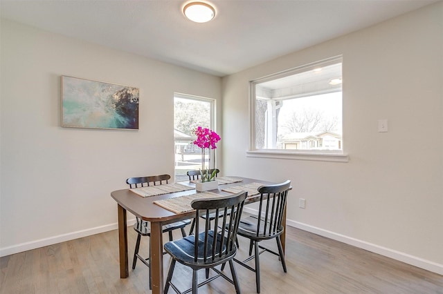 dining space with light wood finished floors and baseboards