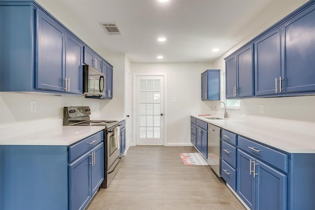 kitchen with stainless steel appliances, blue cabinetry, and light hardwood / wood-style flooring