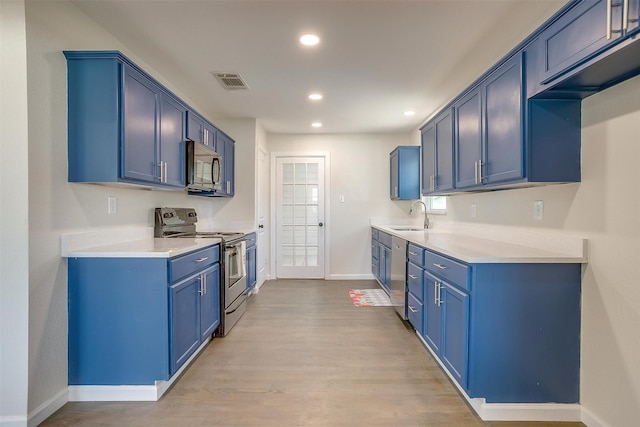 kitchen with recessed lighting, blue cabinets, stainless steel appliances, a sink, and visible vents