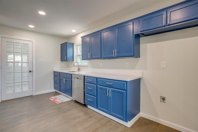 kitchen featuring light countertops, light wood-style flooring, stainless steel dishwasher, a sink, and blue cabinets