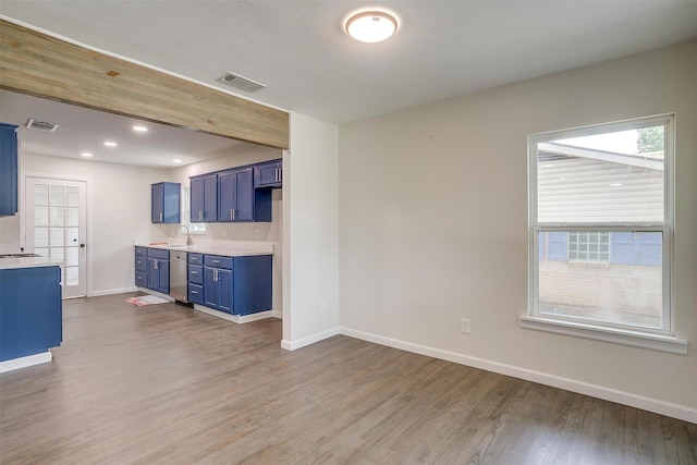 kitchen featuring hardwood / wood-style flooring, stainless steel dishwasher, blue cabinetry, and sink