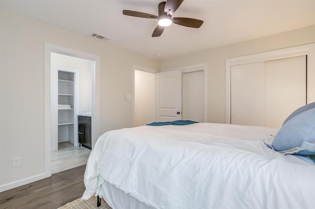 bedroom featuring multiple closets, visible vents, ceiling fan, wood finished floors, and baseboards