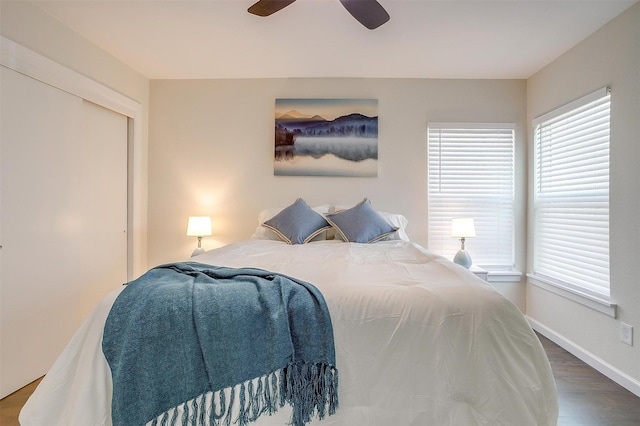 bedroom with ceiling fan, multiple windows, baseboards, and wood finished floors