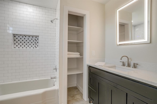 bathroom featuring built in features, tile patterned floors, a walk in closet, vanity, and washtub / shower combination