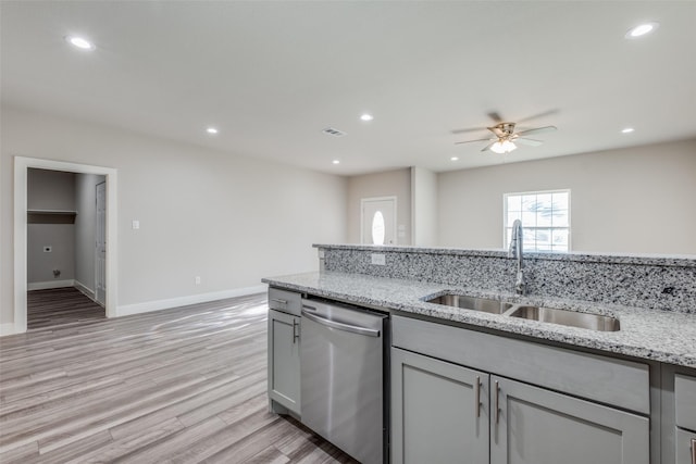 kitchen with stainless steel dishwasher, gray cabinetry, sink, and light stone counters