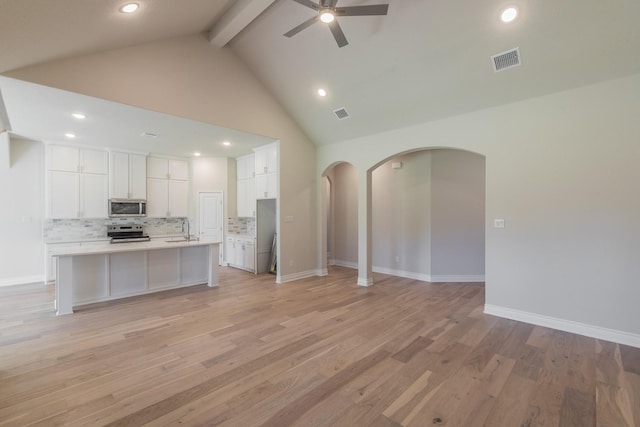 609 Keel Way, Azle, TX 76020 - kitchen featuring appliances with stainless steel finishes, open floor plan, a ceiling fan, beam ceiling, and arched walkways