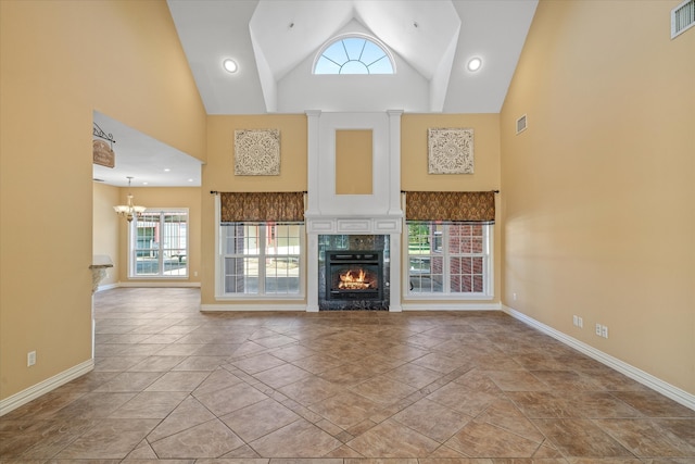 unfurnished living room featuring a fireplace, high vaulted ceiling, light tile patterned flooring, and an inviting chandelier