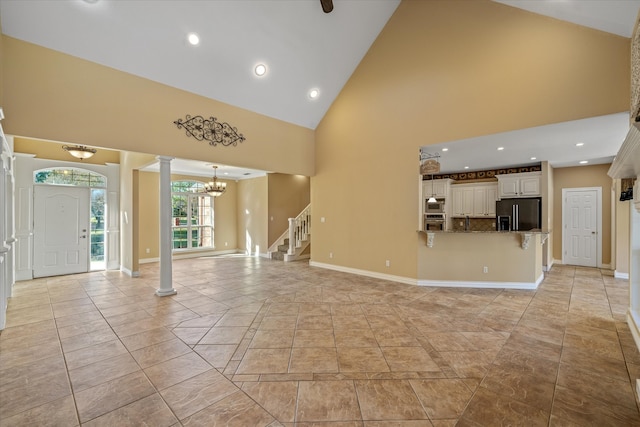 unfurnished living room with high vaulted ceiling and a notable chandelier