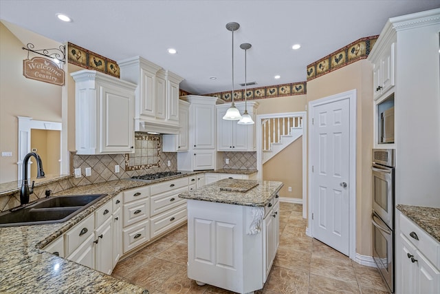 kitchen featuring light stone countertops, a kitchen island, hanging light fixtures, and sink