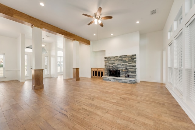 unfurnished living room featuring a fireplace, light hardwood / wood-style floors, ceiling fan, and beamed ceiling