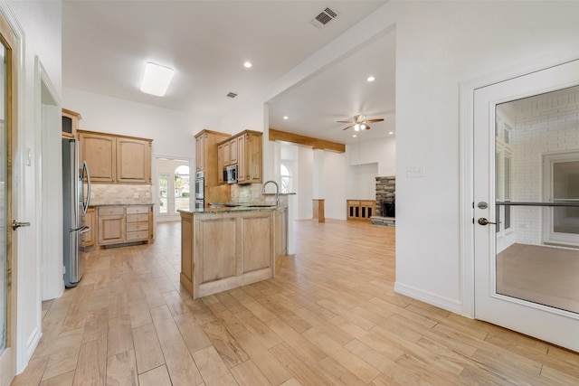 kitchen featuring stainless steel appliances, ceiling fan, a fireplace, and light hardwood / wood-style floors