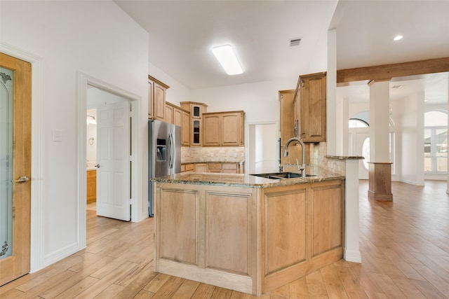 kitchen with sink, tasteful backsplash, light hardwood / wood-style flooring, kitchen peninsula, and stainless steel fridge