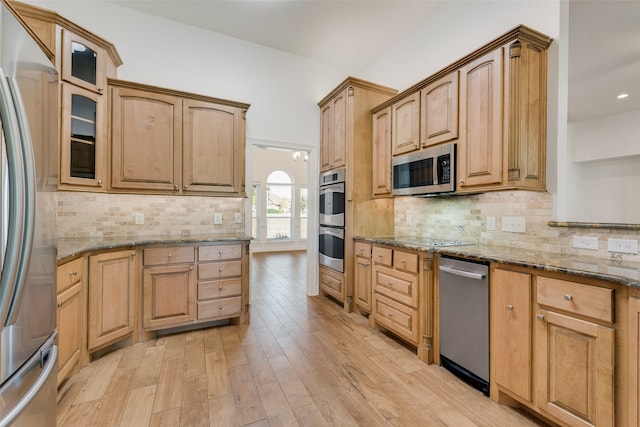 kitchen with decorative backsplash, light hardwood / wood-style floors, light stone countertops, and stainless steel appliances