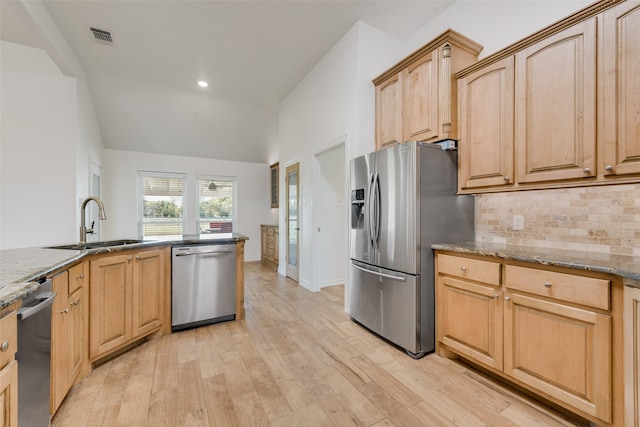 kitchen with light stone countertops, light brown cabinetry, light hardwood / wood-style floors, and appliances with stainless steel finishes