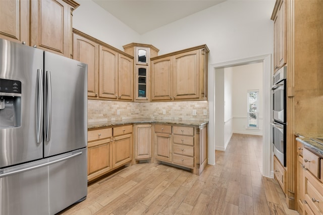 kitchen featuring tasteful backsplash, light stone countertops, appliances with stainless steel finishes, and light hardwood / wood-style flooring