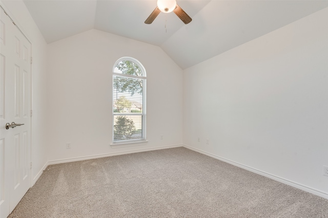 carpeted spare room featuring ceiling fan and vaulted ceiling