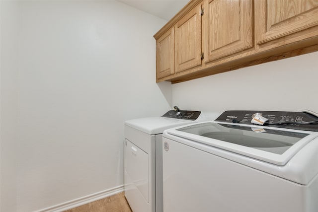 laundry room featuring cabinets, separate washer and dryer, and light wood-type flooring