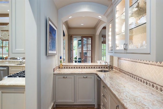 bar with light stone counters, sink, and white cabinets