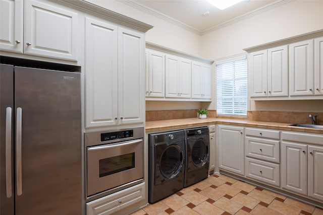 laundry area featuring washing machine and dryer, sink, and ornamental molding