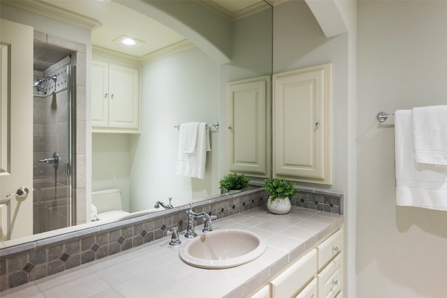 bathroom with tiled shower, vanity, toilet, and crown molding